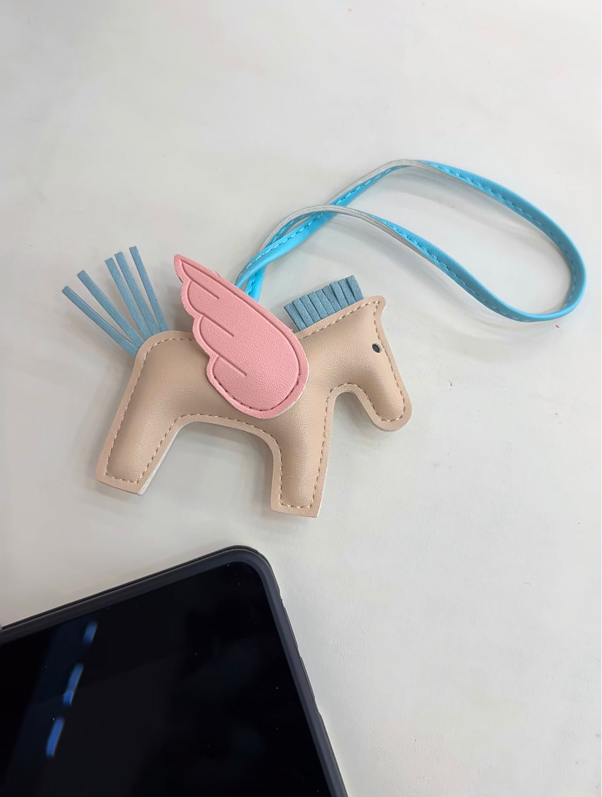 Aster Wing Charmgenuine leather winged horse bag charm attached to a handbag